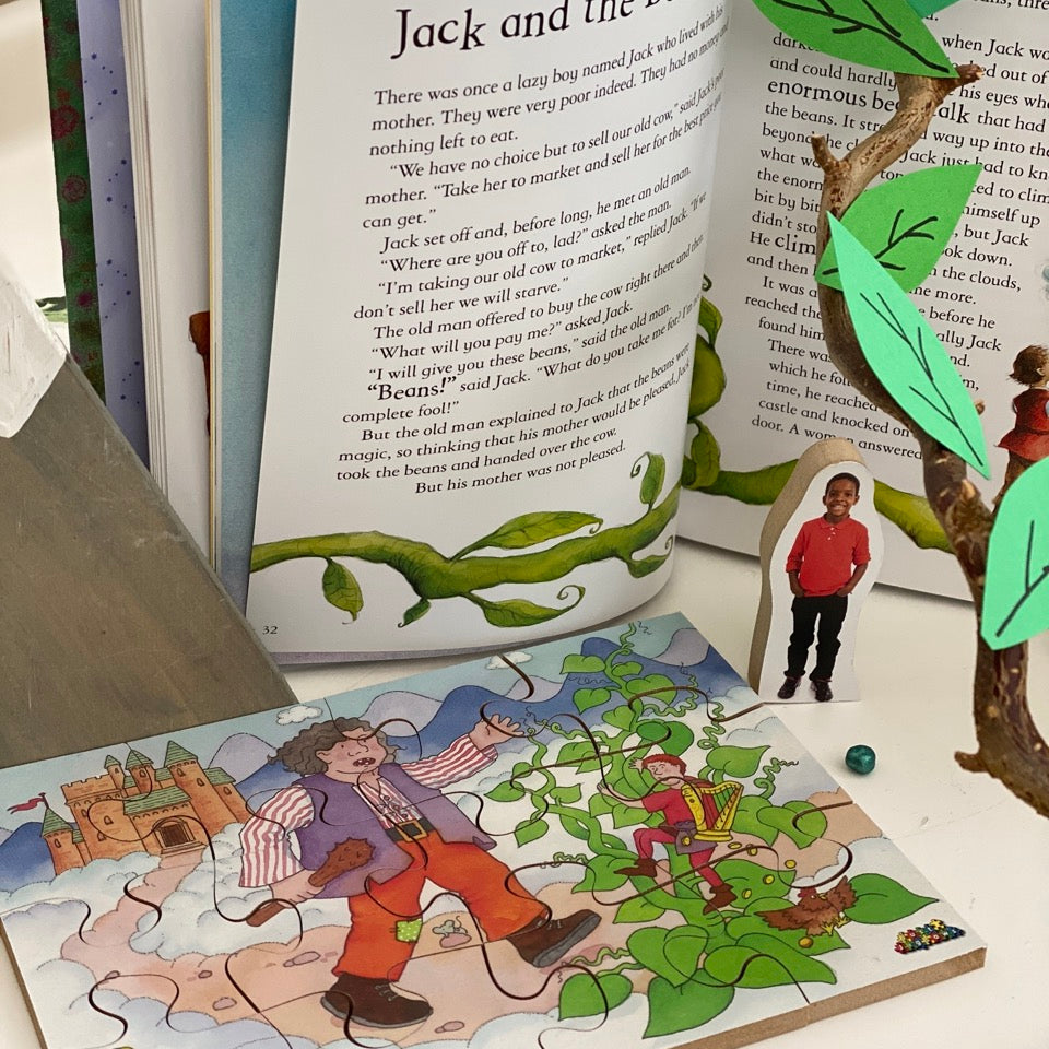 Open book with 'Jack and the Beanstalk' story, puzzle, and beanstalk figure on a table.