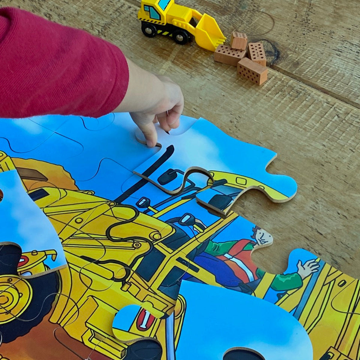 Child playing with a construction-themed puzzle Digger on a wooden floor