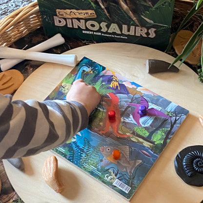 Child playing with a dinosaur peg puzzle toy set on a table