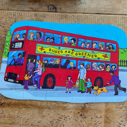 Children's puzzle with a red double-decker bus and people on a wooden surface