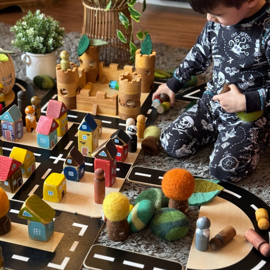 Child playing with toy castle and road set on a rug