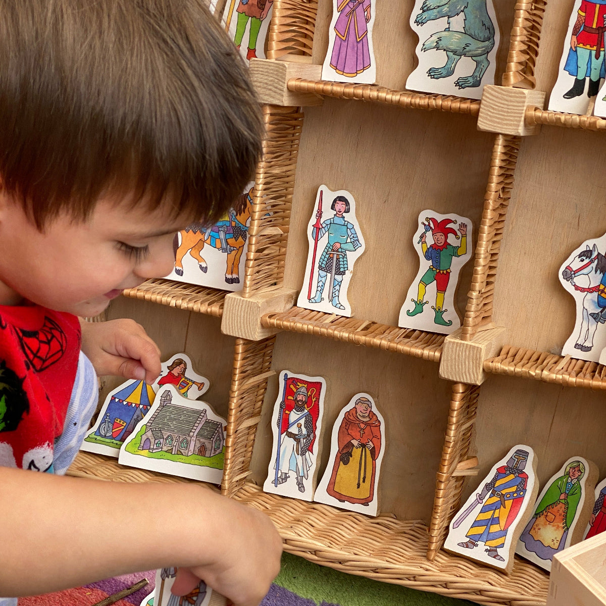 Child playing with colorful fairytale figure pieces on a play shelf.