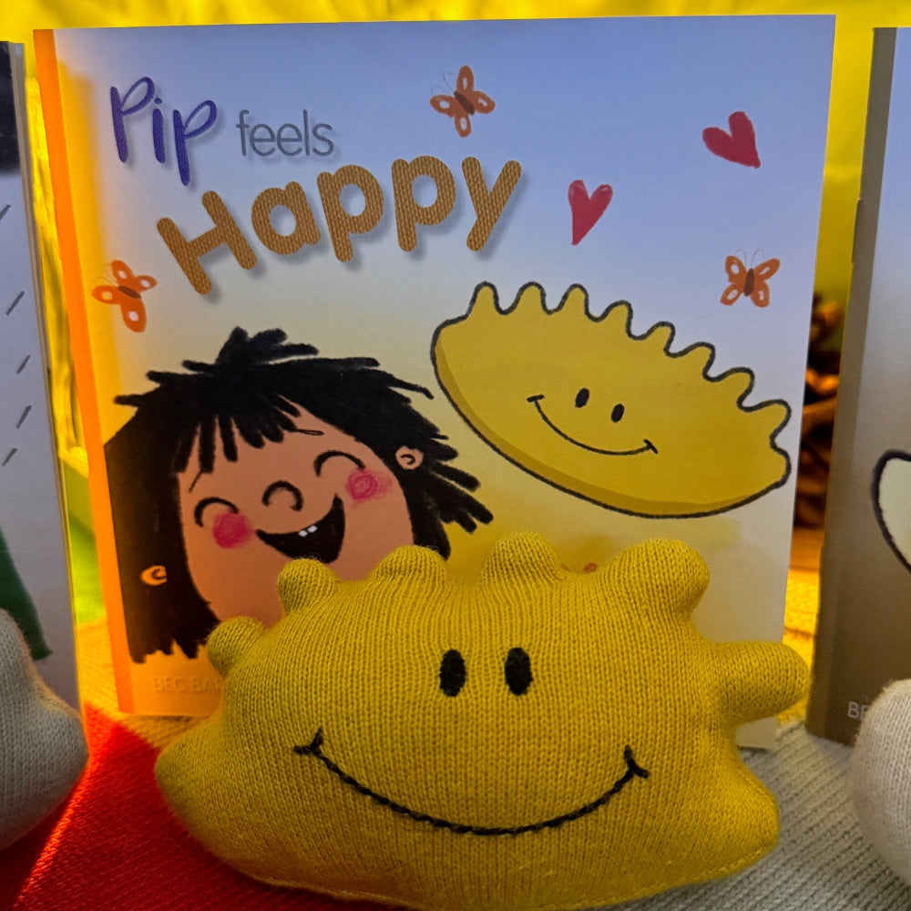 Children's book titled 'Pip Feels Happy' with a yellow plush toy resembling a sun.