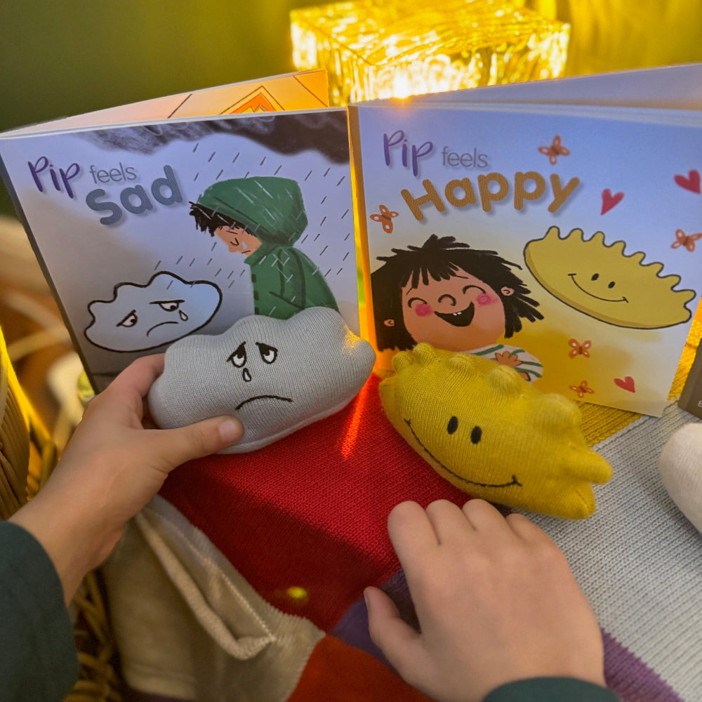 Two children's books titled 'Pip feels Sad' and 'Pip feels Happy' with corresponding plush toys on a colorful surface.