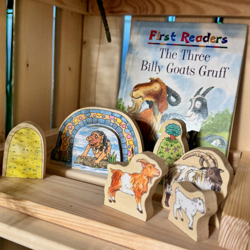 Wooden animal figures and a book titled 'The Three Billy Goats Gruff' on a wooden shelf.