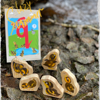 Wooden 5 little duck characters with a small card featuring a duck illustration on a stone background