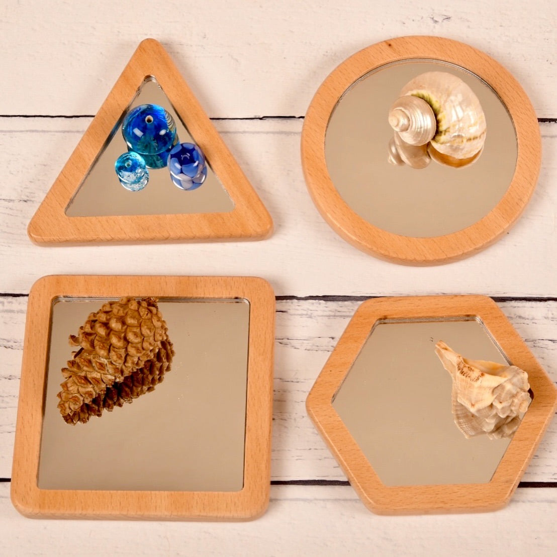 Four wooden-framed mirrors with natural objects on a wooden surface