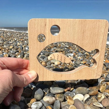 Wooden Fish Shape with pebbles on a pebble beach