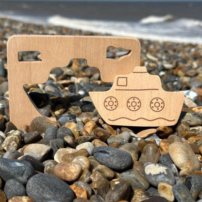 Wooden toy boat shape on pebbles with ocean in the background
