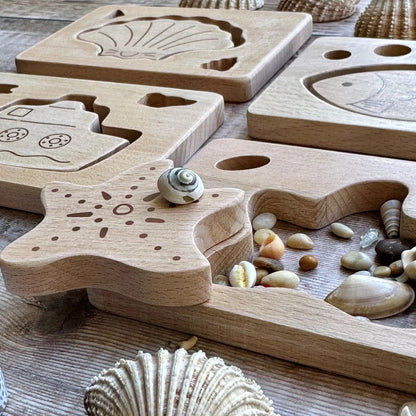Wooden puzzle with shell designs on a wooden surface with seashells and stones.