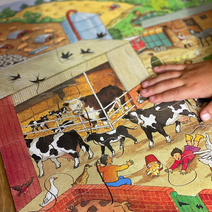 Children's puzzle with farm scene and hand placing a piece.