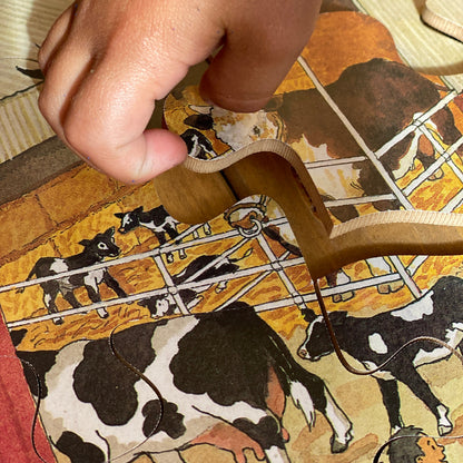 Hand holding a piece of jigsaw puzzle with farm animal cows