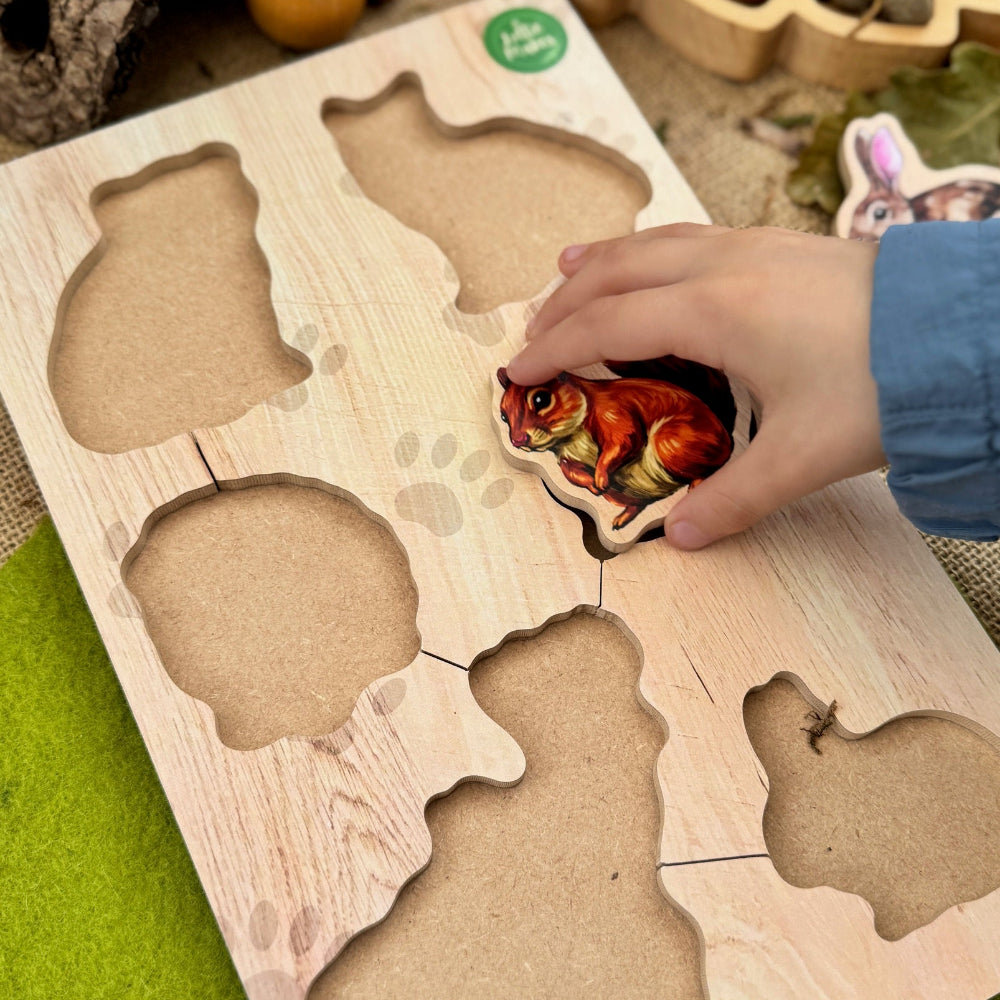 Wooden puzzle with animal shapes on a green surface, surrounded by decorative items.