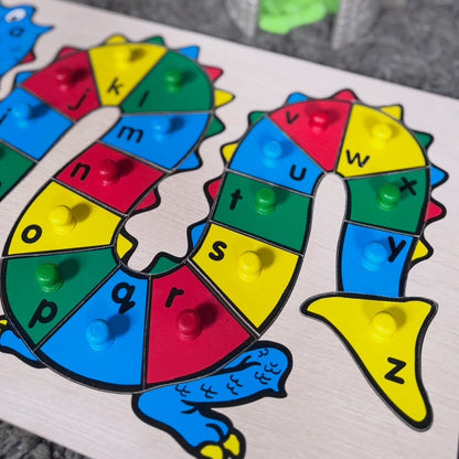 Colorful alphabet puzzle with a dragon design on a gray surface.