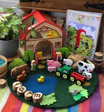 Toy farm set with animals, a house, and educational materials on a colorful rug.