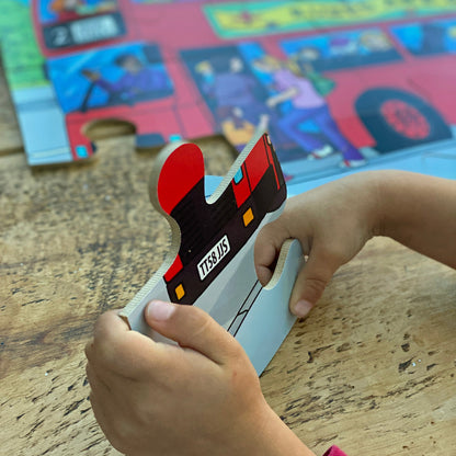 Child playing with a jigsaw puzzle piece on a wooden table with a colorful bus in the background.