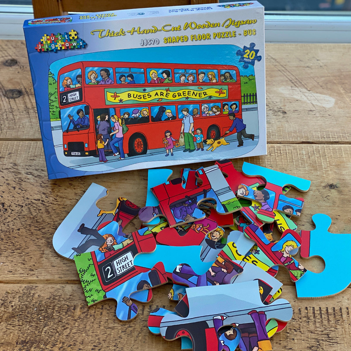 Children's puzzle with bus-themed pieces and packaging on a wooden surface