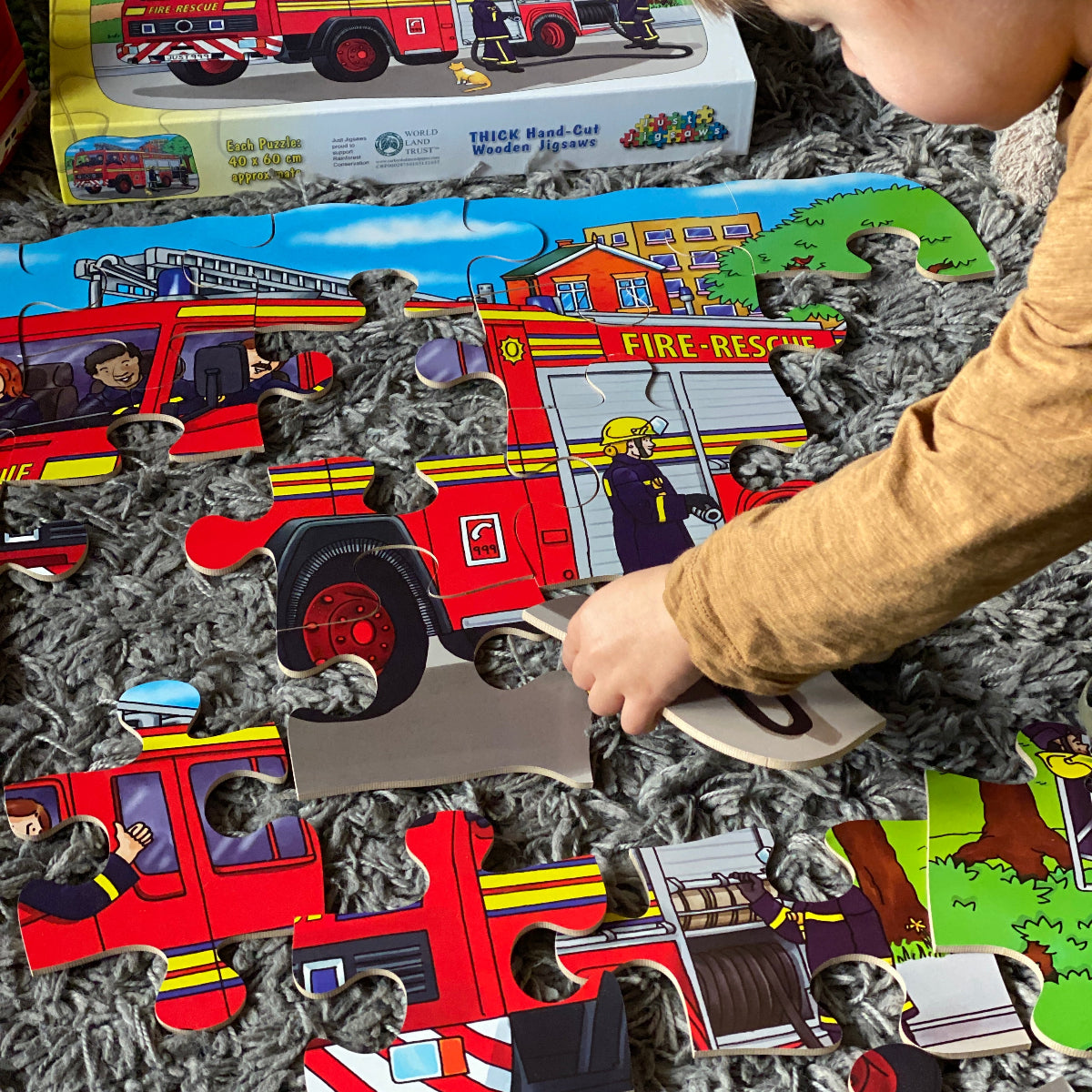 Child playing with a fire truck jigsaw puzzle on a carpeted floor