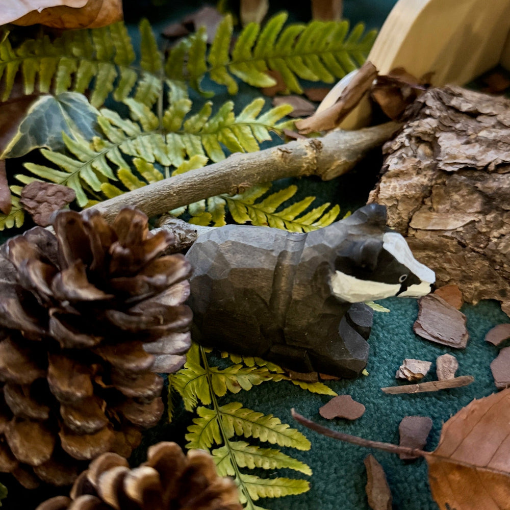 Small hand carved badger toy with pine cones, leaves