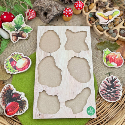 Wooden base board with nature's treasures shapes surrounded by nature-themed decorations on a green surface.