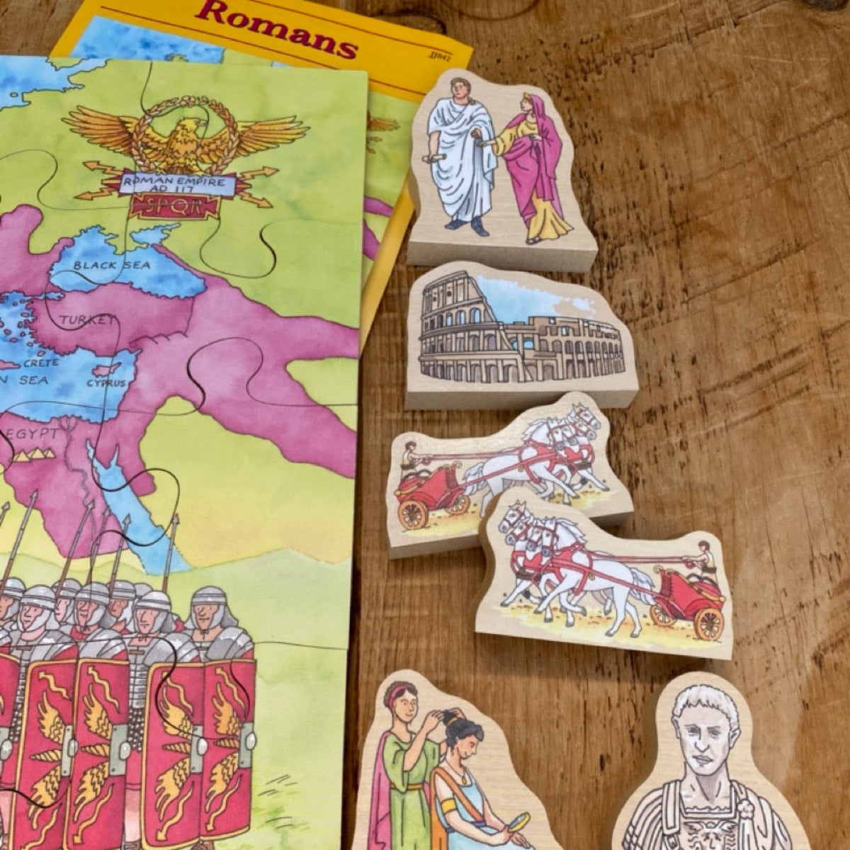 Wooden educational toys on a wooden surface with a map and book titled 'Romans'.