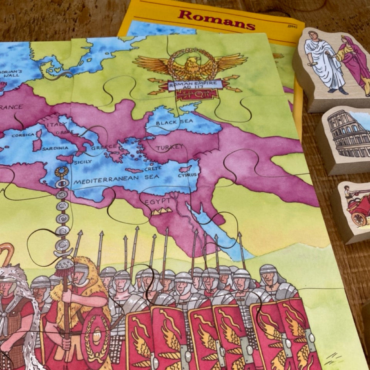 Educational Roman-themed game with map and character pieces on a wooden surface