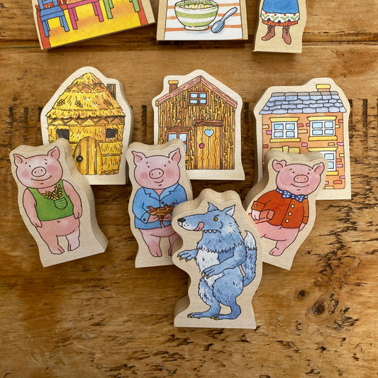 Wooden toys from the story of three pigs and a wolf on a wooden surface
