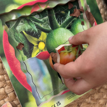 Hand assembling a colorful puzzle of a tomato on a textured surface